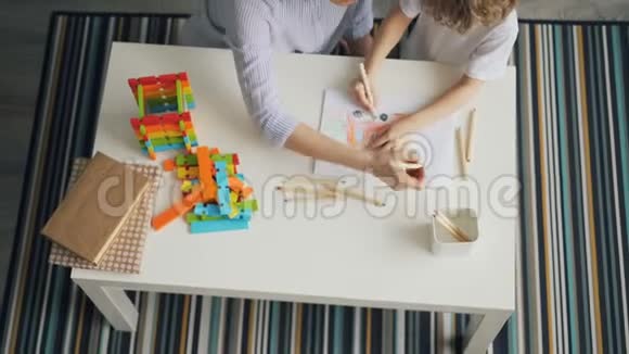 一个年轻的女人和一个孩子一起用铅笔在平板上画画视频的预览图