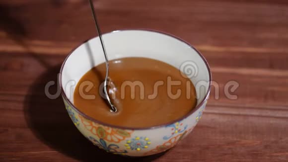 木制桌子上融化的焦糖酱碗视频的预览图