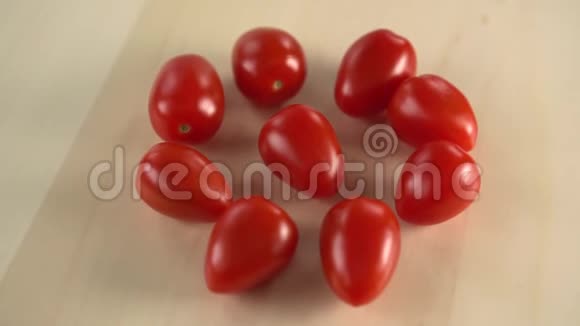 几个红色多汁的樱桃番茄正在木制表面上旋转一股水流用来冲洗上面的水滴视频的预览图