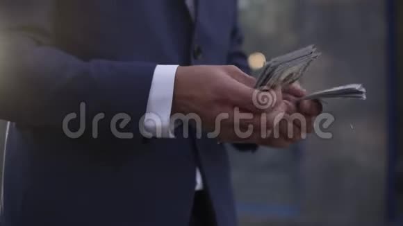 街上面目全非的商人手里拿着一捆美国的钱数着男性财富数视频的预览图