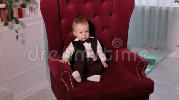 一个一岁小男孩穿着礼服坐在椅子上的肖像视频的预览图