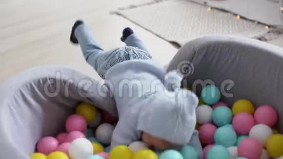 一个笑容满面的小男孩掉进了一个五彩的球池里视频的预览图