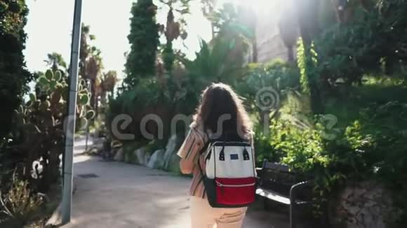 女游客走在热带花园里带着奇异的仙人掌植物视频的预览图