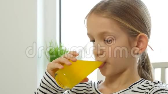 孩子喝橙汁孩子在厨房吃早餐女孩喝新鲜柠檬视频的预览图