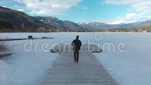 一个白领工人在一个原始的冰盖湖上的木码头上脱下夹克领带跳了下来视频的预览图