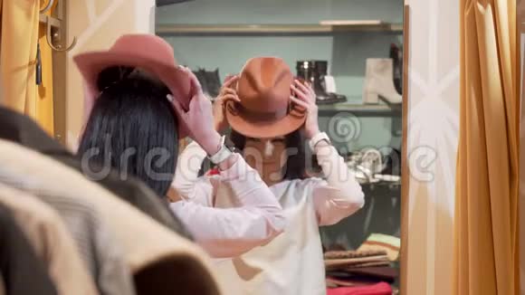 在服装店购物的时候一个漂亮的女人正在试穿一顶新帽子视频的预览图