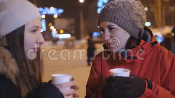两个女孩在圣诞装饰的城市中心喝咖啡玩得开心视频的预览图
