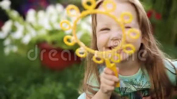 超级可爱的金发小女孩穿着t恤在草地上吹肥皂泡视频的预览图