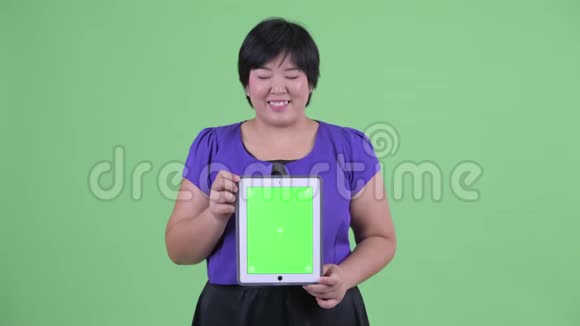 快乐年轻体重超重的亚洲女性在看数字平板电脑视频的预览图