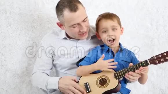 幸福家庭父子俩弹吉他唱歌感受幸福爱快乐和微笑的情感音乐视频的预览图