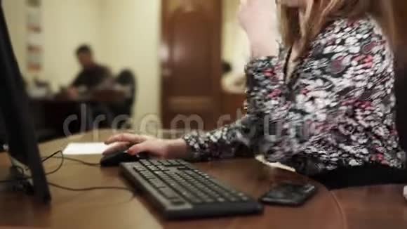 年轻的女同事在她的办公桌上工作在办公室用电脑视频的预览图