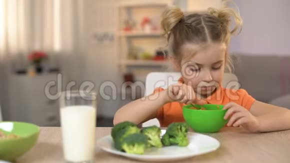可爱的女儿吃早餐麦片和牛奶母亲抚摸女孩的头视频的预览图