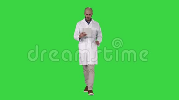 成熟的男性医生拿着数字平板电脑使用它走在绿色屏幕上Chroma键视频的预览图