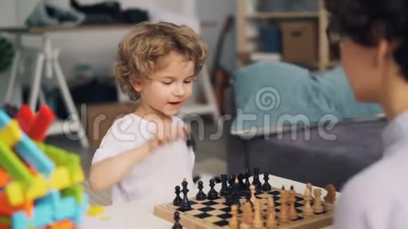 妈妈教可爱的男孩下棋而孩子正在玩有趣的移动棋子视频的预览图