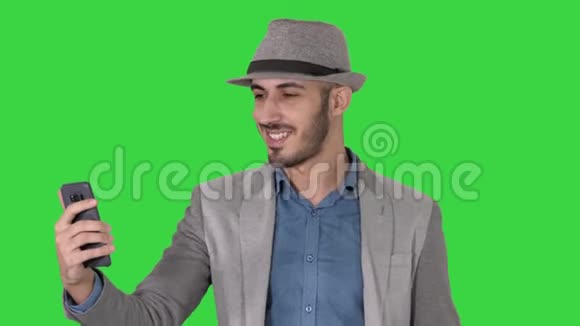 有魅力的男人穿着休闲服装帽子时髦的风格记录Vlog或视频呼叫绿色屏幕Chroma键视频的预览图