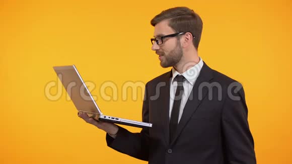 快乐的自由职业者拿着笔记本电脑眨眼和展示一堆美元成功视频的预览图
