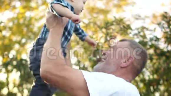 快乐的祖父把他的孙子举起来吻他的胃祖父和孙子户外肖像画视频的预览图