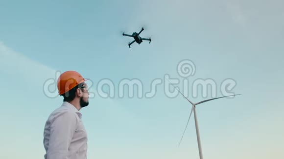 戴着橙色防护头盔和护目镜的白种人工程师观看了一架智能四翼无人机的工作视频的预览图