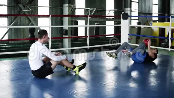 两个肌肉发达的人在健身房训练一起做腹部俯卧撑并在运动过程中投掷重球视频的预览图