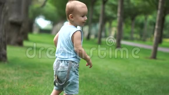 一个可爱的蹒跚学步的孩子正慢吞吞地在公园里散步视频的预览图