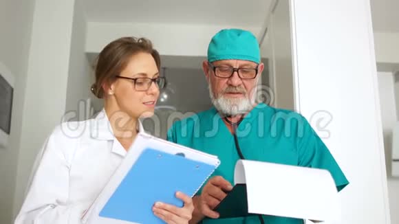 漂亮的一对夫妇两个医生一男一女穿着医用长袍手里拿着文件夹看着框架微笑着视频的预览图