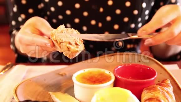 女人手抹在可爱的咖啡馆里的面包鸡肉酱上法式早餐视频的预览图