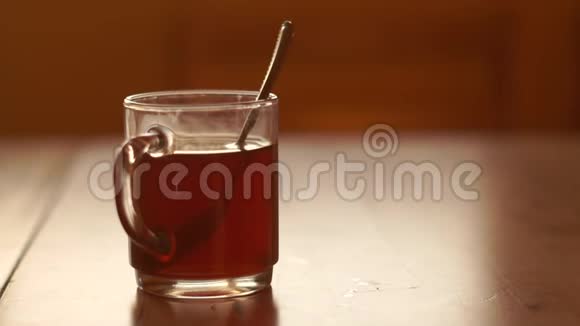 一杯透明的茶立在桌子上里面有一个铁勺在朝阳下视频的预览图