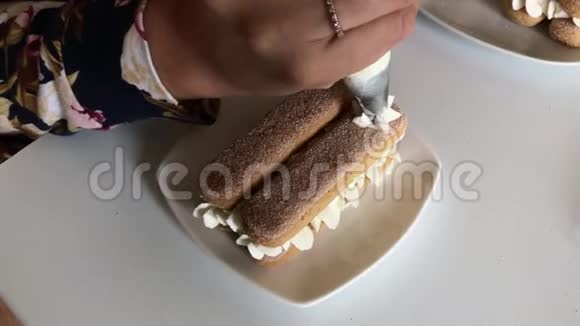 一个女人正在做蛋糕莱斯萨维亚迪饼干在一层与奶油混合使用糕点袋涂抹奶油视频的预览图
