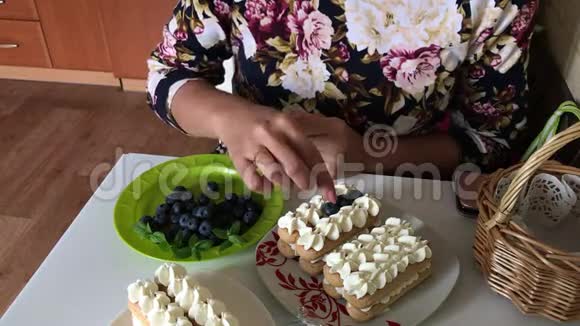一个女人正在做蛋糕一层的萨沃亚迪饼干和奶油层以蓝莓装饰视频的预览图