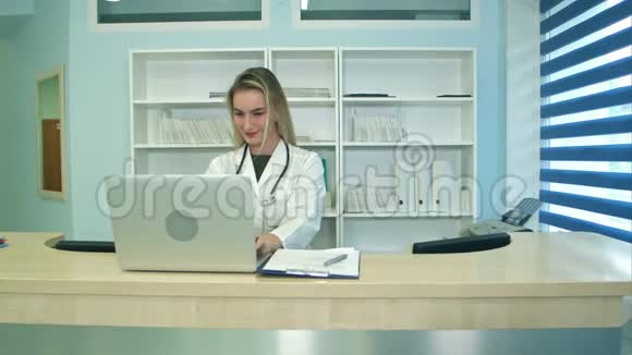 微笑医疗护士在笔记本电脑上工作在前台做笔记视频的预览图