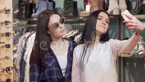 快乐的女性朋友在服装店用智能手机自拍视频的预览图