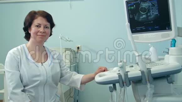 微笑女医生坐在超声诊断仪旁边视频的预览图