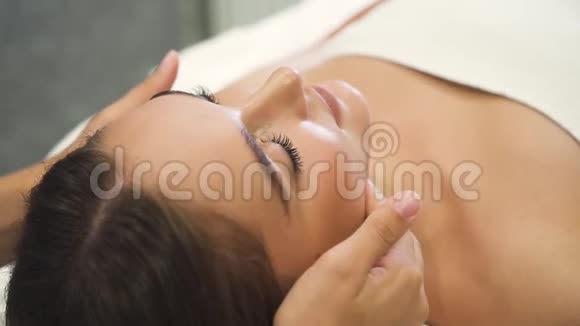 专业美容师在水疗沙龙按摩女性客户的脸视频的预览图