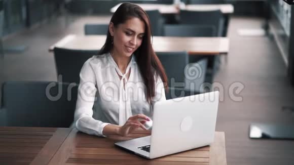年轻成功的女商人坐在夏季咖啡馆里手提电脑慢动作视频的预览图