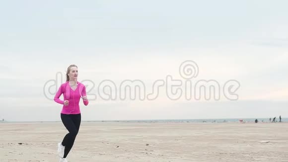 美丽的女孩在海边奔跑健身训练欧洲女性耳机视频的预览图