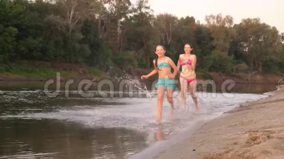 快乐的孩子们沿着海滩奔跑女孩们在沙滩上奔跑在海滩上溅起水滴笑着快乐和快乐视频的预览图