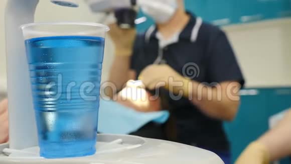 现代牙科办公室的模糊牙科程序文字空间前景上有蓝色液体的普拉蒂斯杯视频的预览图