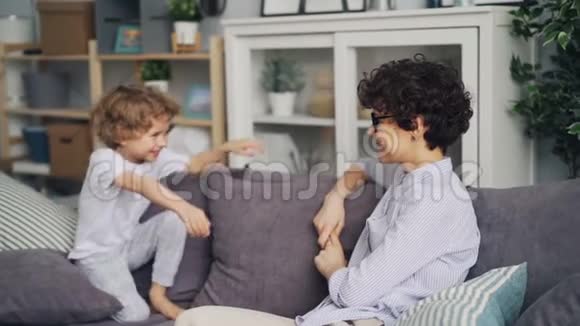 爱的母亲和小儿子在家里坐在沙发上拥抱的慢动作视频的预览图