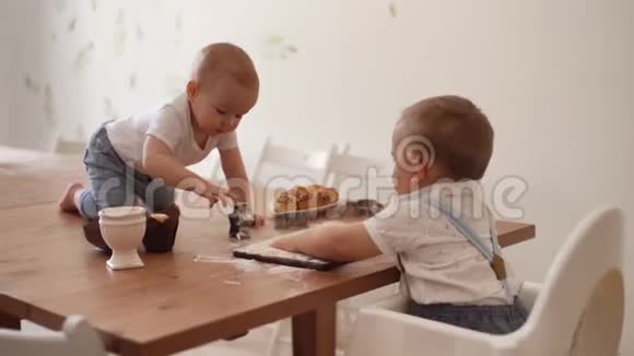 两个孩子在厨房里玩餐具放在一张铺着面粉的桌子上视频的预览图