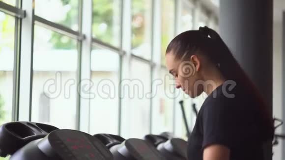 年轻女孩在健身房跑步机上跑步视频的预览图
