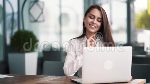 年轻成功的女商人坐在夏季咖啡馆里手提电脑慢动作视频的预览图