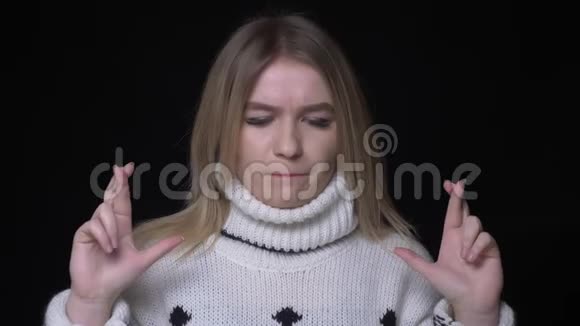 穿着毛衣的年轻漂亮白种人女性特写镜头手指交叉着希望和焦虑的目光视频的预览图