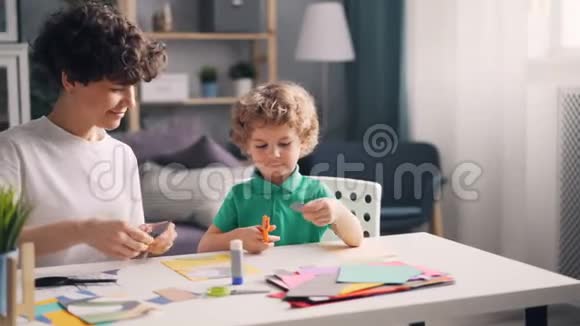 母亲和儿子正忙着在家里的餐桌上创作彩色纸拼贴画视频的预览图
