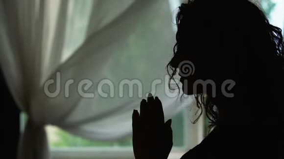 女人的剪影在室内祈祷双手交叉阅读祈祷问上帝视频的预览图