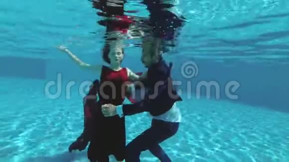 一对相爱的夫妇新娘和新郎穿着婚纱在游泳池的水下游泳他们微笑享受玩耍视频的预览图
