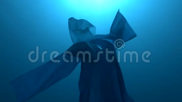 蓝色塑料雨衣作为幽灵慢慢漂浮在蓝色的水中海底塑料污染海洋视频的预览图