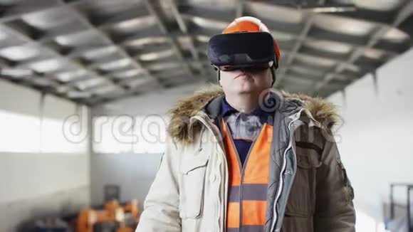 戴着安全帽穿着工作服的人正站在机库的中间戴着虚拟现实眼镜的人在驾驶着钻头视频的预览图