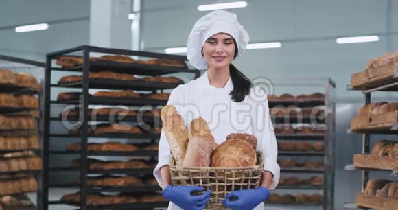 一个可爱的乡村小女孩面包店老板拿着一篮子新鲜面包笑起来很可爱视频的预览图