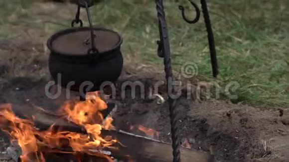 在户外的营地里黑色金属烹饪锅着火了在营火上准备食物视频的预览图
