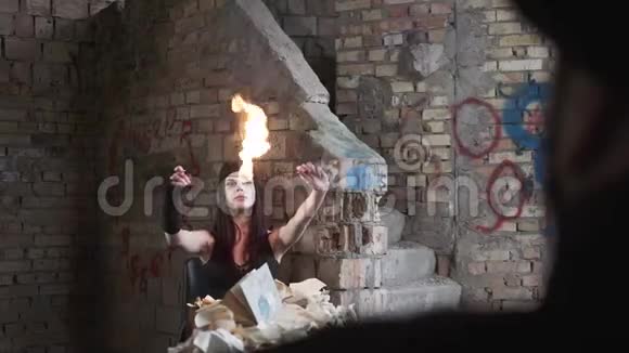 白脸的年轻女子吹灭了墙前废弃建筑里的火秀的概念火灾视频的预览图